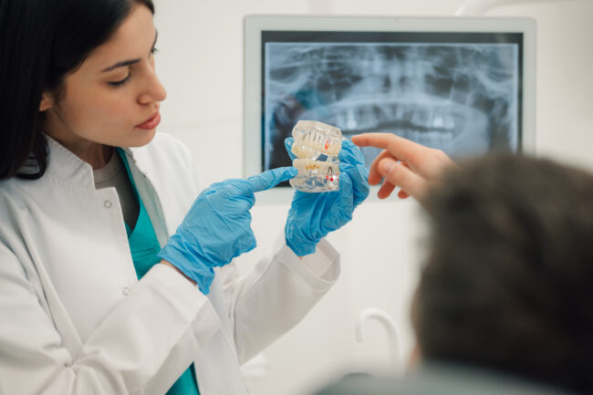 Dentist showing teeth model to patient in dental clinic